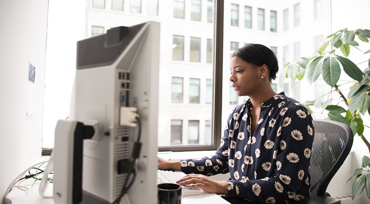 lady in office sitting at desk and working on computer