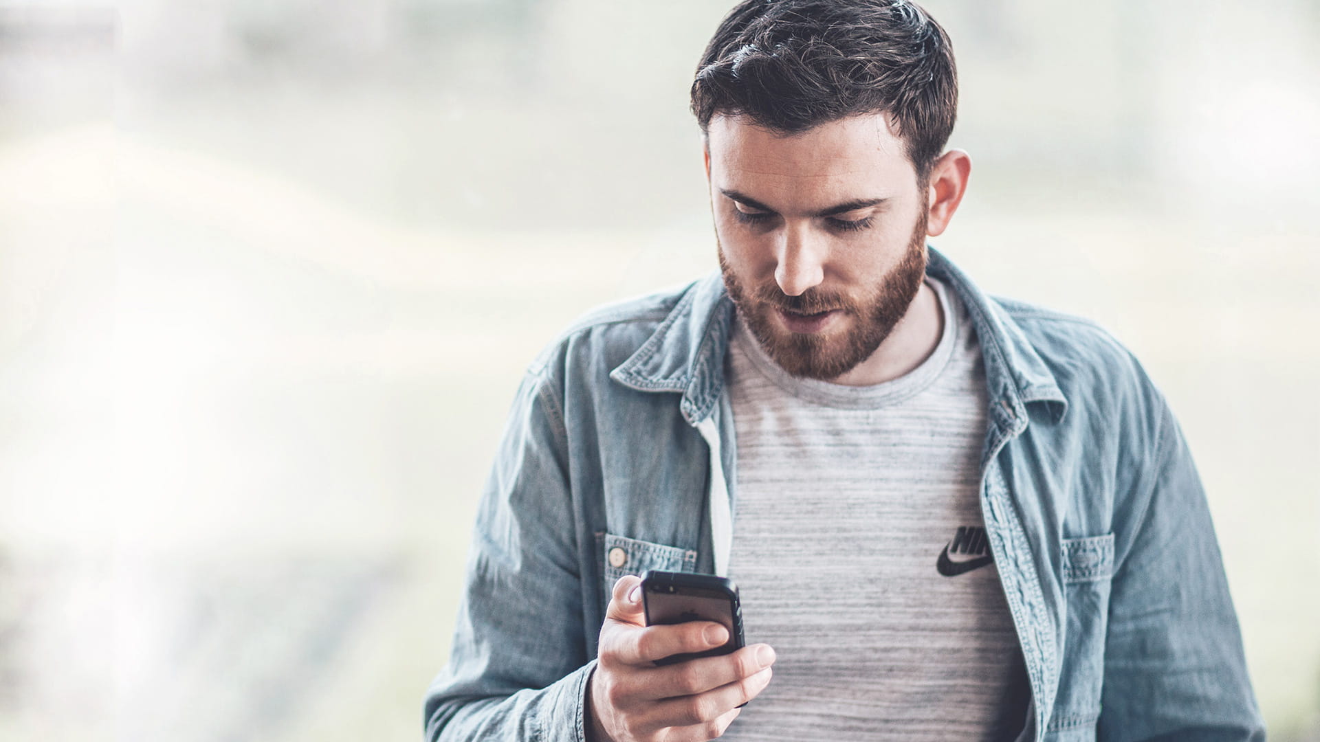Bearded man calculating his super contribution on smartphone