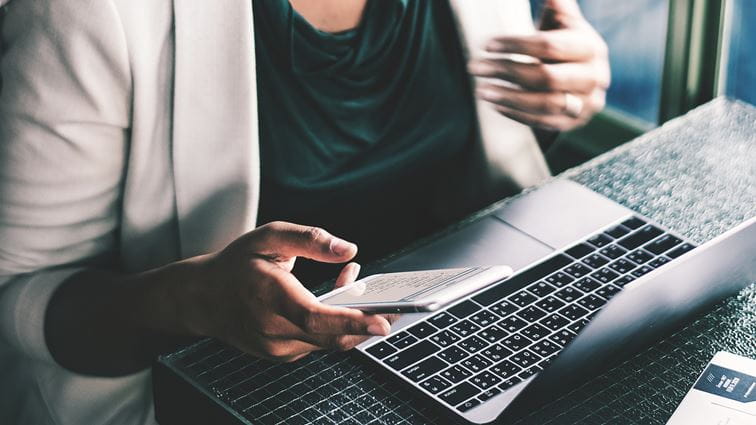 A woman using her phone and computer