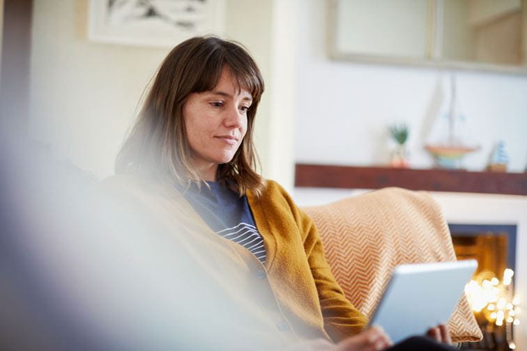 Woman using digital tablet in living room