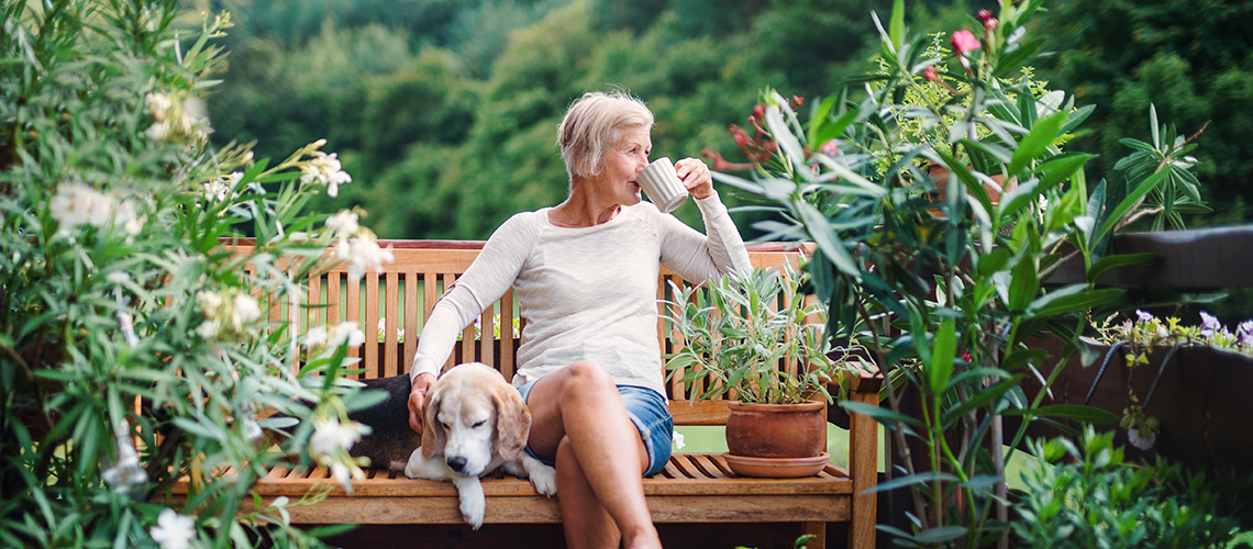 woman on patio with a dog drinking from a mug