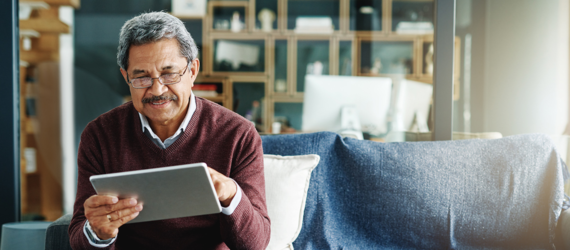 man sitting on his couch looking at a tablet