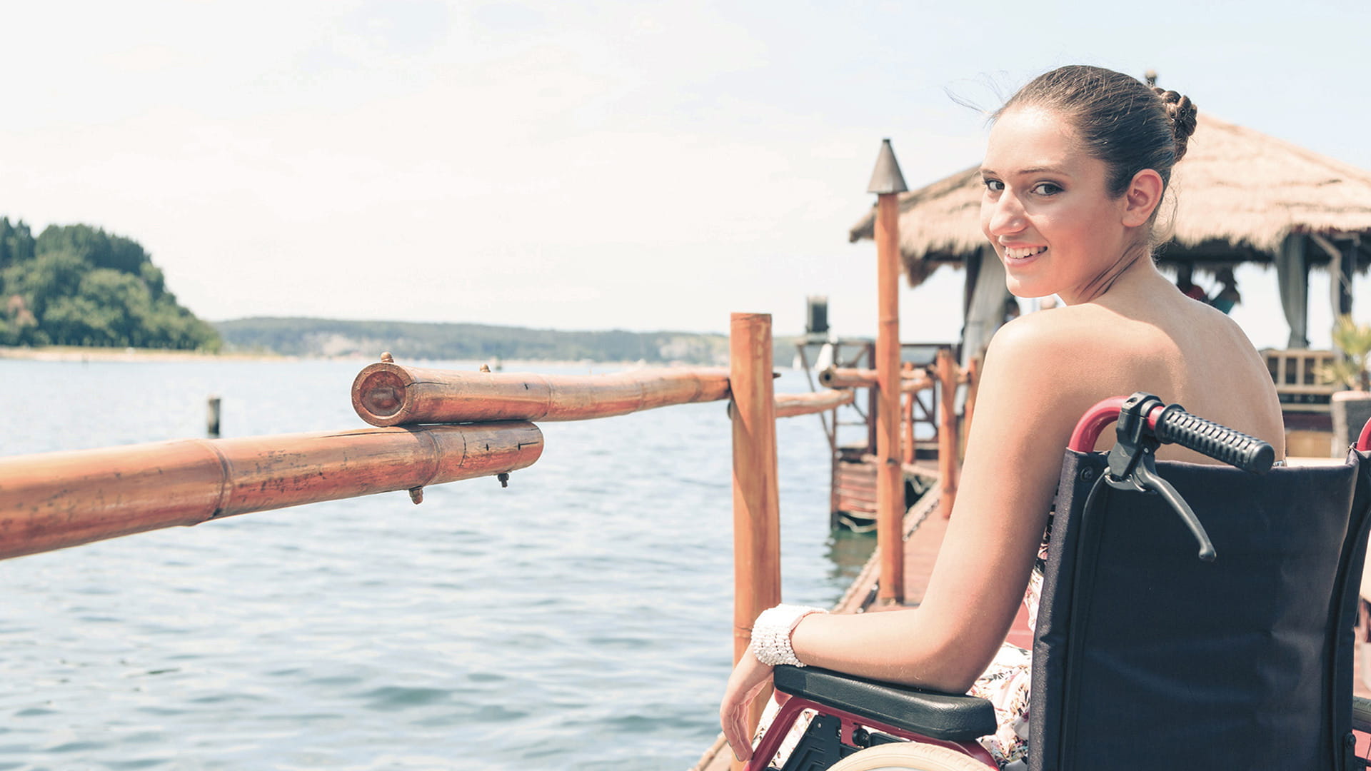 Woman in wheelchair at seaside smiling