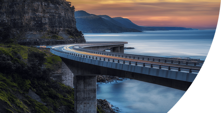 Sunset over the sea cliff bridge along the Australian Pacific Ocean coast with lights trails from cars