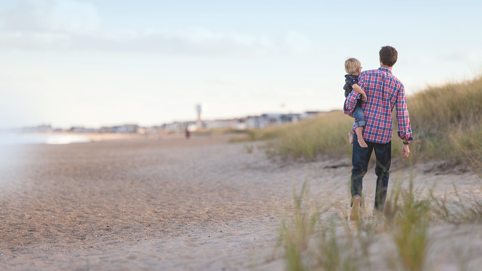 Father and young child walking along beach